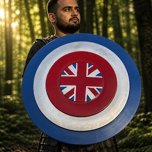 May include: A round shield with a blue, silver, and red color scheme. The center features a red circle with a Union Jack design. The shield is held in front of a person in a forest setting.