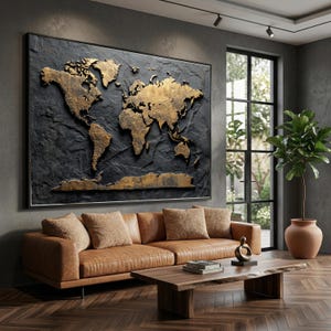 May include: A large framed wall art piece featuring a gold-colored world map against a dark gray textured background. The artwork hangs above a brown leather sofa with matching throw pillows. A wooden coffee table and a potted plant complete the living room setting.