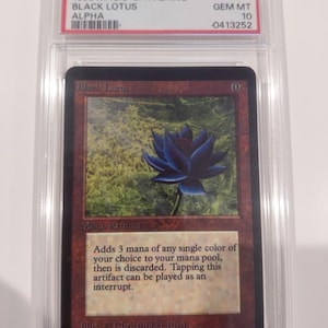 May include: A graded Magic: The Gathering card, "Black Lotus" from 1993. The card features a dark blue lotus flower illustration on a maroon background. The card is encased in a protective holder with the text "GEM MT 10".