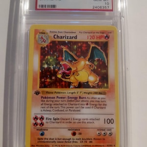 May include: A graded 1999 Pokémon Game Charizard card. The card features a vibrant illustration of Charizard, a flame Pokémon, with a 170 cm length and 90 kg weight. The card is encased in a protective case with a label indicating its grade.