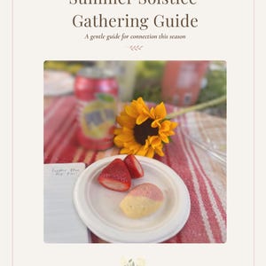 Op de afbeelding: Een Summer Solstice Gathering Guide document met een foto van een wit bord met gesneden aardbeien en een klein gebakje, een felgele zonnebloem, een rood drankblikje en een notitieboekje met handgeschreven tekst op een gestreepte doek.