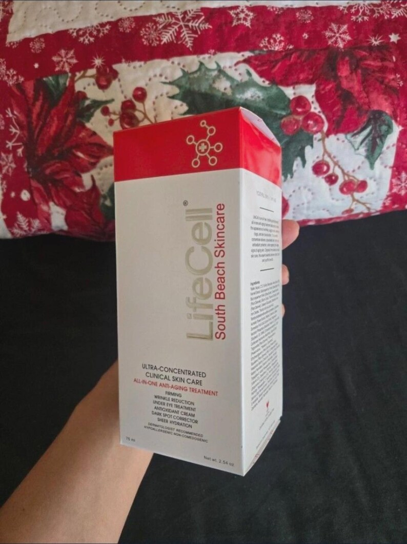 K&ouml;nnte beinhalten: Eine wei&szlig;e und rote Schachtel von LifeCell South Beach Skincare. Die Schachtel tr&auml;gt den Text &bdquo;Ultra-konzentrierte klinische Hautpflege All-in-One Anti-Aging-Behandlung&ldquo;. Die Schachtel wird vor einem festlichen rot-wei&szlig; gemusterten Hintergrund gehalten.