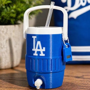 May include: A blue and white water cooler featuring the LA logo. The cooler has a white handle, a clear straw, and a small blue tag attached. It is on a wooden surface.