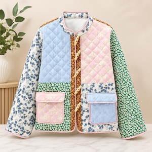 May include: A quilted jacket featuring a patchwork design of floral, striped, and solid patterns in blue, pink, green, and brown. The jacket has a mandarin collar, long sleeves, two front pockets, and is fastened with four light-coloured toggle buttons.