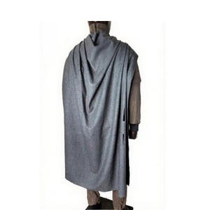 May include: A gray cape with a textured, speckled appearance. The cape drapes over a person's shoulders and back, reaching almost to the ankles. The person is wearing a brown jacket and pants. The cape has a button closure on the side.