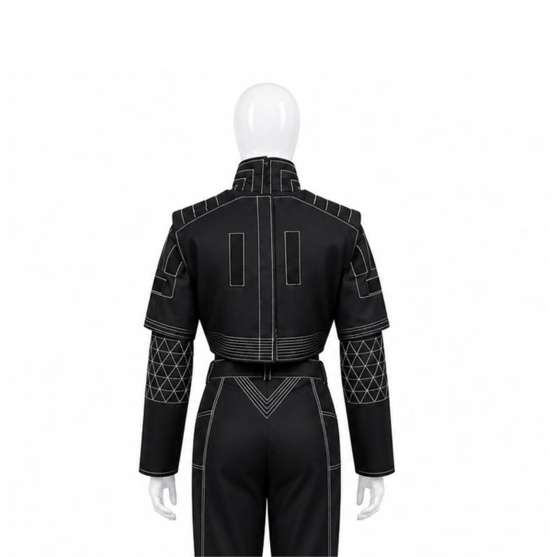 May include: Black two-piece outfit with white stitching. The cropped jacket features geometric patterns on the sleeves. The high-waisted trousers have a V-shaped design at the waist. The outfit is displayed on a mannequin.