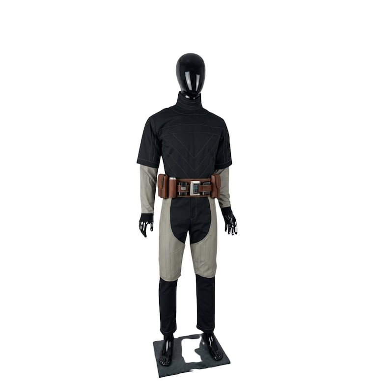 May include: A black and gray costume displayed on a mannequin. The outfit includes a short-sleeved top, pants, and a belt with pouches. The mannequin is black and stands on a black base. The costume has a futuristic or tactical design.