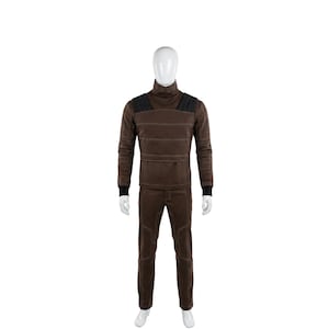 May include: A brown turtleneck long-sleeve shirt and matching pants set. The shirt has black shoulder accents and horizontal stitching. The pants have knee patches. The set is displayed on a mannequin against a white background.