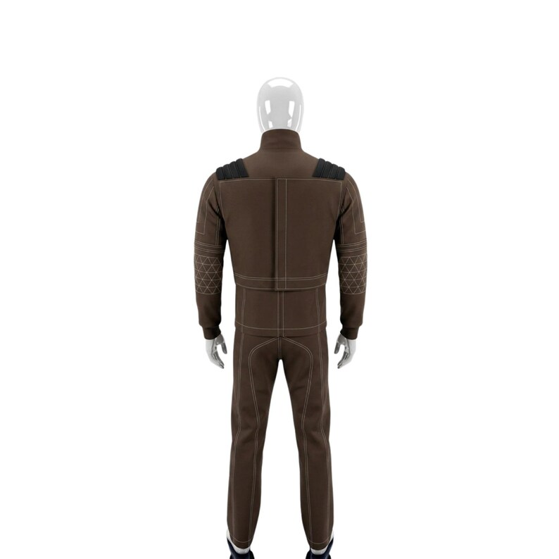 May include: A brown jumpsuit with white stitching and black shoulder accents. The jumpsuit has a high collar and long sleeves. The sleeves and shoulders have a geometric design. The pants are straight-legged.