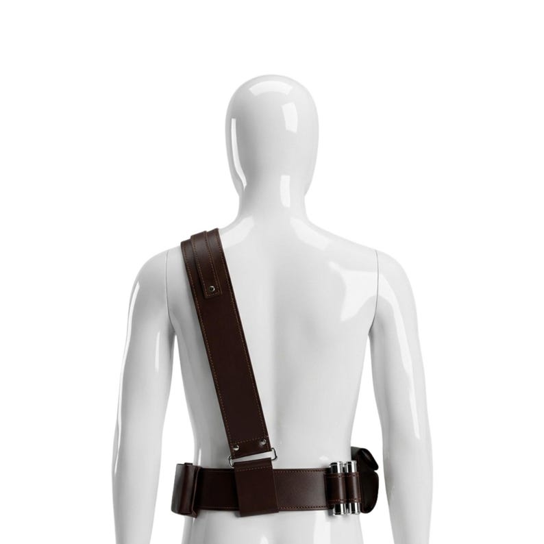 May include: A brown leather belt and shoulder strap set. The belt has a rectangular buckle and several cartridge holders. The shoulder strap is wide and attaches to the belt. The set is displayed on a white mannequin.