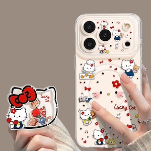 以下が含まれることがあります： 赤いリボンをつけた白い猫のキャラクター、小さなテディベア、赤い花が描かれた透明なスマートフォンケースとスマホグリップ。表面にはLucky Catという文字、音符、本、電話のアイコンがプリントされています。