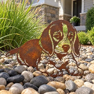 Peut inclure: Une silhouette en métal couleur rouille représentant un chien aux longues oreilles tombantes avec une finition texturée. Le design découpé présente des traits faciaux détaillés, incluant les yeux et le museau, et montre le chien assis.