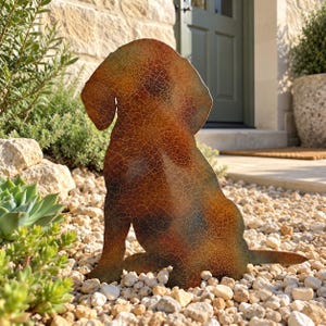 May include: A flat metal silhouette of a sitting dog featuring a weathered, multi-coloured finish with a distinct crackled texture. The surface displays blended tones of deep brown, rust orange, and hints of dark green across the entire shape.