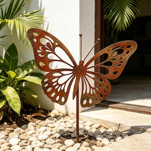 May include: A metal butterfly garden stake featuring a weathered, rusted brown finish with a crackled texture. The butterfly has intricate cut-out patterns on its wings and two thin, straight antennae extending upward from the central body.