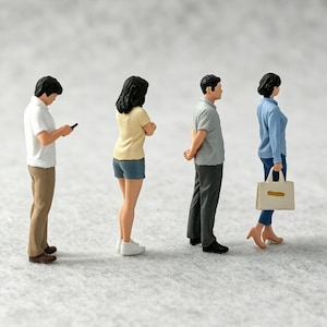 May include: A set of four miniature figurines standing in a line. The first figure wears a white polo and tan pants, the second a yellow t-shirt and blue shorts, the third a gray polo and dark trousers, and the fourth a blue shirt and blue pants.