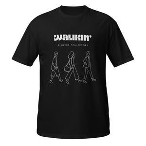 Puede incluir: Camiseta negra con la palabra "WALKIN'" y la frase "AIMLESS TRAJECTORY" en blanco. Debajo, un dibujo lineal blanco de tres personas caminando. Una camiseta informal.