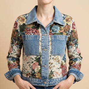 Puede incluir: Una chaqueta de manga larga que combina paneles de mezclilla azul claro y una tela color crema con un patrón de tapiz floral multicolor. La chaqueta incluye un cuello clásico, cierres de botones metálicos y dos bolsillos frontales.