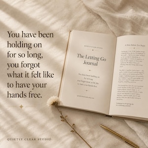Op de afbeelding: Een open dagboek getiteld The Letting Go Journal met donkerbruine tekst op crèmekleurige pagina's. De linkerpagina bevat het citaat: You have been holding on for so long, you forgot what it felt like to have your hands free. Een gouden pen ligt ernaast.