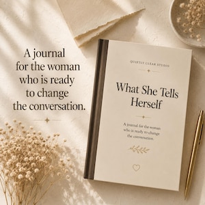 Pode incluir: Um diário de capa dura com uma capa cor de creme e uma lombada castanho-escura. A capa apresenta o texto "QUIETLY CLEAR STUDIO", "What She Tells Herself" e "A journal for the woman who is ready to change the conversation.", com um pequeno ícone de folha e coração.