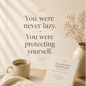 Op de afbeelding: Een beige Procrastination Breakthrough Worksheet boekje met donkerbruine tekst die luidt: You were never lazy. You were protecting yourself. Een bijpassende beige gespikkelde mok en een vaas met droogbloemen staan op een houten ondergrond.