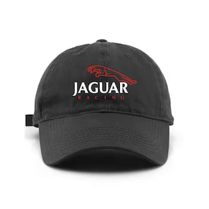 May include: A black baseball cap featuring the red Jaguar leaping cat logo above the white text JAGUAR and the red text RACING centered on the front panel. The cap has a curved brim and a structured crown with visible stitching details.
