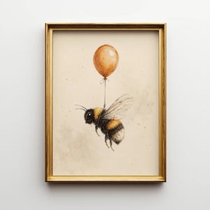 May include: A framed art print featuring a watercolor illustration of a bumblebee suspended by a brown balloon. The bee has black and yellow stripes, with transparent wings. The artwork is set against a beige background, framed in a gold-colored frame.