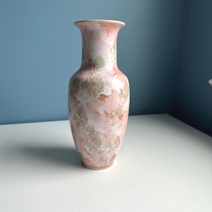 Könnte beinhalten: Eine dekorative Vase mit ausgestelltem Rand. Die Vase hat ein marmoriertes Design in Rosa, Weiß und Braun. Diese Keramikvase ist ein dekorativer Artikel, der sich zum Ausstellen von Blumen oder als eigenständiges Akzentstück eignet.