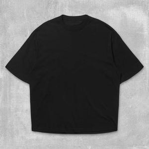 May include: A solid black, oversized t-shirt with a crew neck and short sleeves. The shirt is made of a soft material and has a relaxed fit. The background is a textured, light gray surface.