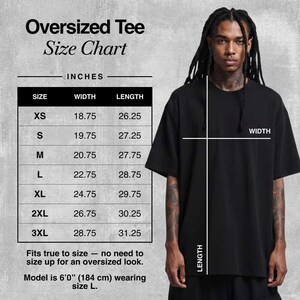 May include: A black oversized tee shirt with a size chart in inches. The chart lists sizes XS to 3XL with width and length measurements. The model is 6'0" tall and wearing a size L.