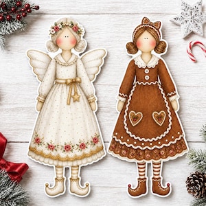 May include: Two flat decorative doll cutouts. The left doll is an angel in a cream dress with gold dots, a floral hem, and wings. The right doll wears a brown dress with white scalloped trim, heart-shaped pockets, and a matching brown hair bow.