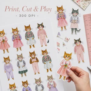 K&ouml;nnte beinhalten: Ein digitales Druckblatt mit mehreren illustrierten Katzen in verschiedenen Outfits wie rosa Kleidern, Blumenoberteilen und Latzhosen. Der Text Print, Cut & Play - 300 DPI ist oben sichtbar. Ein rosa Lineal befindet sich auf der rechten Seite.