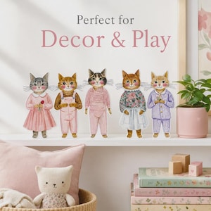 K&ouml;nnte beinhalten: F&uuml;nf illustrierte Katzenfiguren stehen in einer Reihe und tragen verschiedene Kleidungsst&uuml;cke wie Kleider, Latzhosen und Schlafanz&uuml;ge. Der Text dar&uuml;ber lautet Perfect for Decor & Play. Die Katzen haben detaillierte Fellmuster und Gesichter.