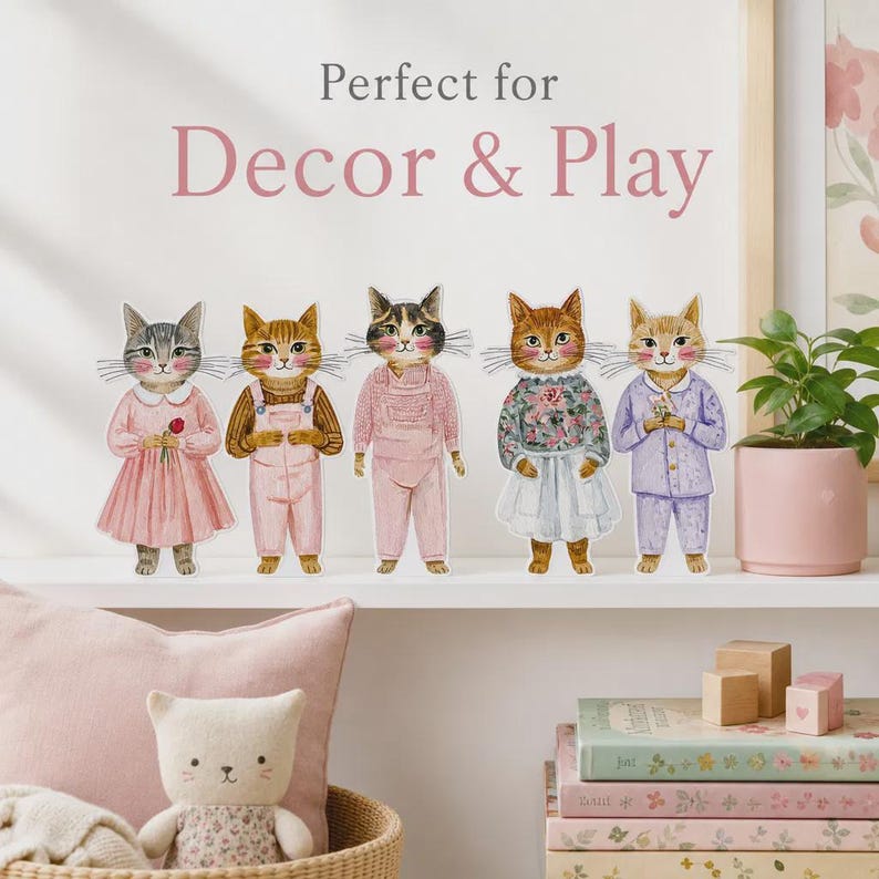 K&ouml;nnte beinhalten: F&uuml;nf illustrierte Katzenfiguren stehen in einer Reihe und tragen verschiedene Kleidungsst&uuml;cke wie Kleider, Latzhosen und Schlafanz&uuml;ge. Der Text dar&uuml;ber lautet Perfect for Decor & Play. Die Katzen haben detaillierte Fellmuster und Gesichter.
