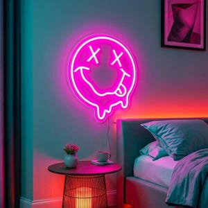 May include: A circular neon sign featuring a bright pink glowing smiley face with X-shaped eyes and a tongue sticking out, with a dripping effect at the bottom edge. The sign is mounted on a wall above a small round table and a bed.