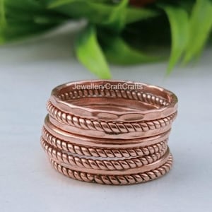 May include: A stack of copper rings with different textures, including hammered and rope-like designs. The rings are stacked together, displaying the various styles. The text "JewelleryCraftCrafts" is visible on the top ring.