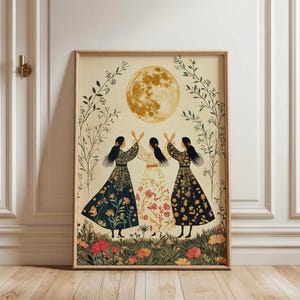 Könnte beinhalten: Gerahmter Kunstdruck mit drei Figuren in langen Kleidern, die die Arme zu einem großen, goldenen Mond erheben. Die Figuren stehen in einem Feld aus Blumen und Grün. Das Kunstwerk hat einen Vintage- und Folk-Art-Stil.