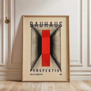 May include: Framed Bauhaus art print featuring a geometric design with the word "BAUHAUS" at the top. The print has a red vertical rectangle in the center, with the word "PERSPEKTIVE" below it. The words "BOLD GEOMETRY" and the number "109" are also visible.