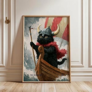 May include: A framed wall art print depicting a black cat wearing a grey horned Viking helmet and a red cape, standing in a wooden boat on a stormy sea. The text THE BLACK CAT 193 is printed in the lower section of the artwork in black lettering.