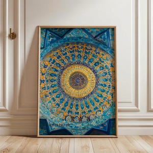 May include: Framed print featuring a detailed, circular design in shades of blue and gold, reminiscent of Islamic art. The word "IRAN" is displayed at the bottom, with "WORLD CULTURE" below it. The artwork is displayed on a wooden floor against a white wall.