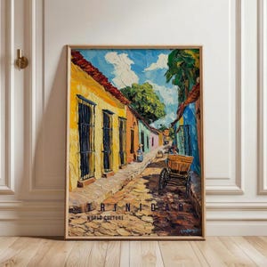 Peut inclure: Une impression de peinture à l'huile représentant une rue de Trinidad avec des bâtiments jaunes, orange et bleus, une route pavée et une charrette en bois. Le texte TRINIDAD WORLD CULTURE est imprimé en bas de l'œuvre dans un cadre en bois.