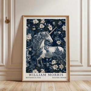 May include: A framed vertical art print featuring a white unicorn with a spiraled horn set against a dark blue background of dense foliage and white flowers. The text at the bottom reads WILLIAM MORRIS BOTANICA-056 SILVER HORN in black font.