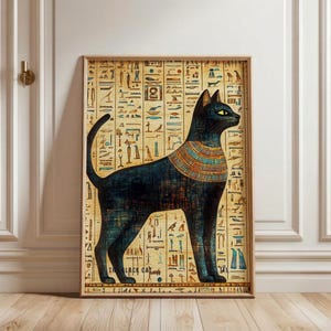 May include: A framed wall art print featuring a stylized black cat with yellow eyes and a colorful striped collar, set against a background of beige papyrus paper covered in rows of ancient Egyptian hieroglyphs and the text THE BLACK CAT.