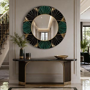 May include: A round wall mirror featuring a decorative frame with alternating black and dark green fan-shaped segments accented by thin gold lines. The mirror is mounted on a light gray wall above a dark console table with gold metal trim.