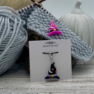 May include: Two witch hat stitch markers, one pink and one black, with a silver clasp and a black cord. The stitch markers are on a white card with the text "acorn & owl".