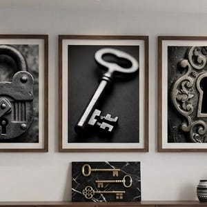 May include: Three framed black and white prints of antique locks and keys. The prints are in brown frames and are displayed above a decorative shelf. A small marble plaque with gold keys is on the shelf, along with decorative vases.