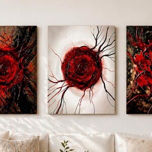 Puede incluir: Tres pinturas abstractas sobre lienzo con un diseño central rojo que se asemeja a una rosa o un sol. La obra de arte presenta fondos oscuros con pinceladas texturizadas y líneas ramificadas, creando una exhibición dramática y artística.
