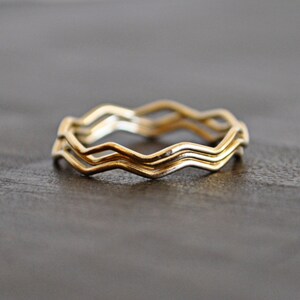 May include: Three gold rings stacked together, each ring has a wavy, zig-zag design.