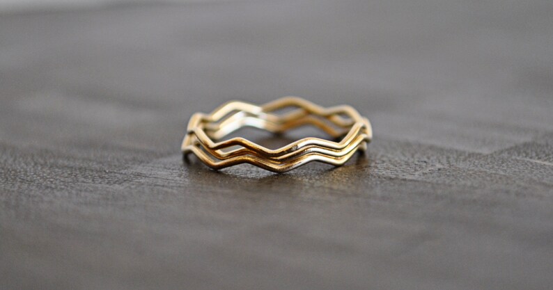 May include: Three gold rings stacked together, each ring has a wavy, zig-zag design.