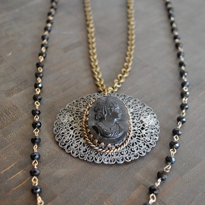 May include: A black cameo pendant necklace with a filigree design and a black beaded chain.