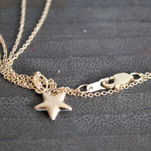 May include: A gold chain necklace with a star pendant and a lobster clasp closure.